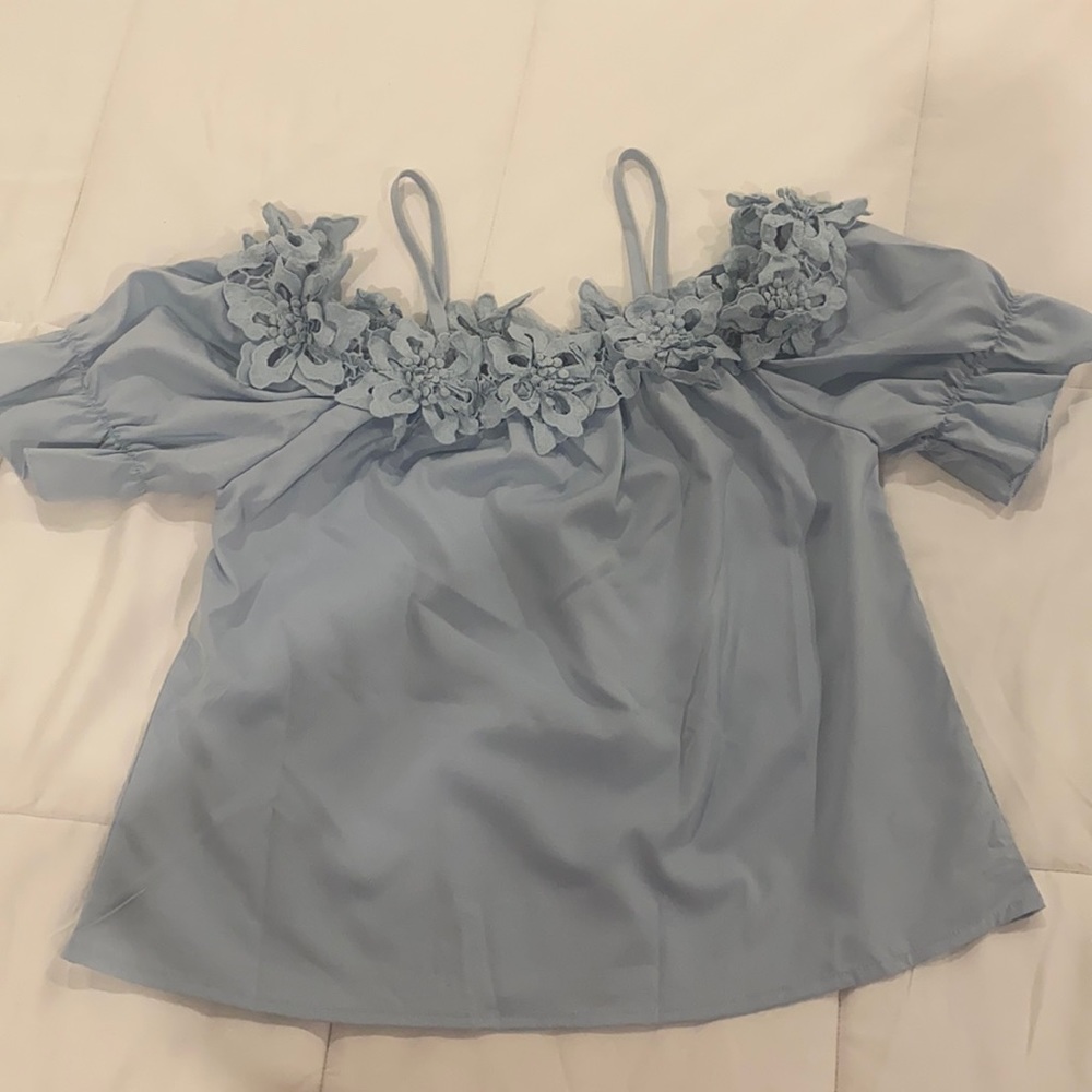 Light blue flower appliqué , cold shoulder top. Brand new.